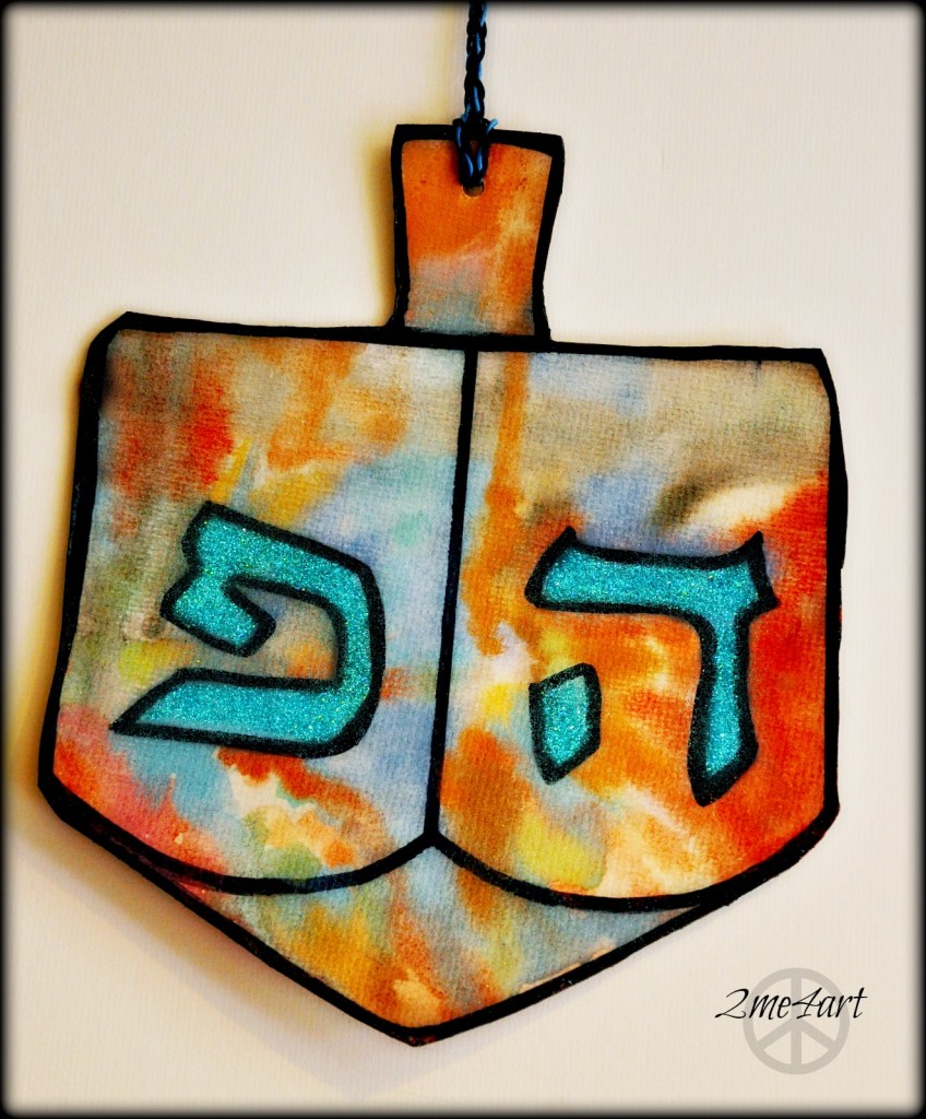 This dreidel was painted on matt board by a 6 year old with watercolor & glittered later…
