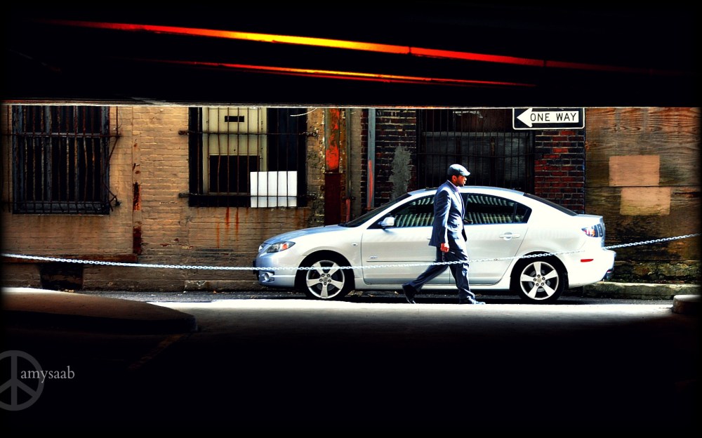 this well-dressed man passed in front of this parked car. i photographed this looking opposite an abandoned parking deck. reflections can be seen in the windows of the car. You can also see light reflected from the steel beams on the ceiling. Downtown Birmingham, Alabama.